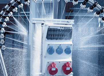 Eine AMAXX® Steckdosenkombination von MENNEKES wird im Prüflabor mit Wasser bespritzt.