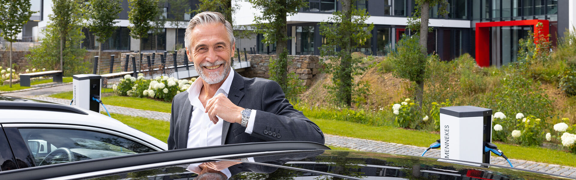 Unternehmer auf seinem Firmenparkplatz mit Ladesäulen von Mennekes